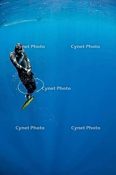 Freediver tries to swim through the bubble air ring at the depth of Blue Hole, Dahab, Egypt [IBR125382609]