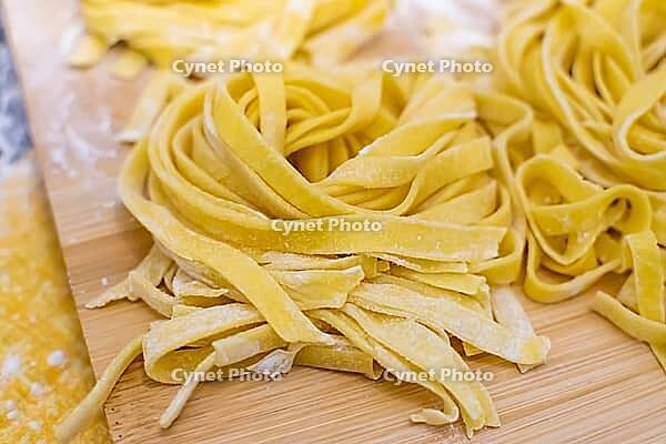 Close up of hands making home made italian pasta with flour, eggs and pasta machine [IBR125382613]