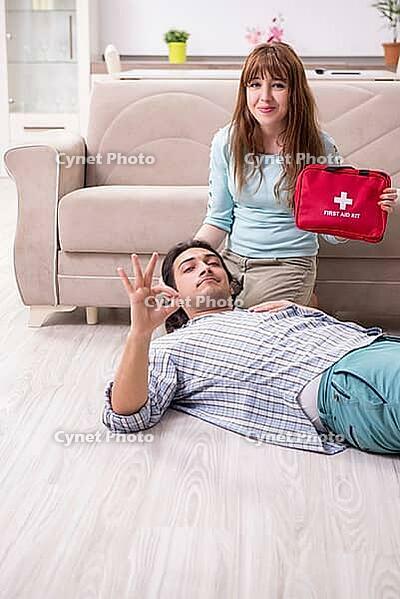 The young couple in a first aid concept at home [IBR125382614]
