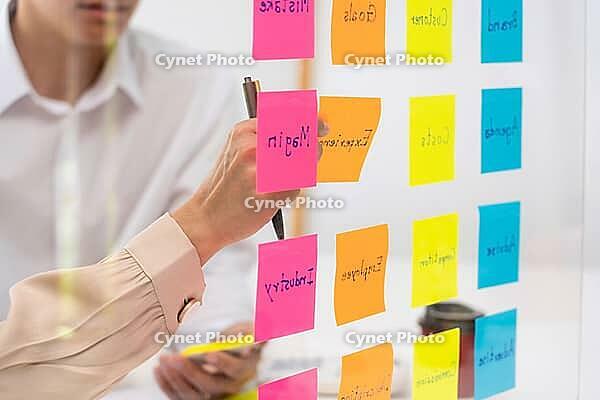 Business people planning startup project placing sticky notes session to share idea on glass wall, Strategy Analysis Office Concept [IBR125382619]