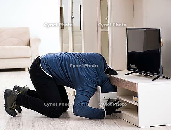 The burglar steals television from the house [IBR125382621]