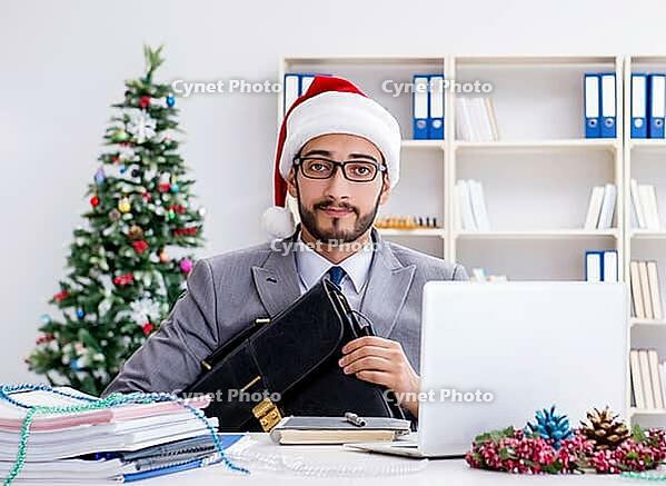 The young businessman is celebrating Christmas in the office [IBR125382650]