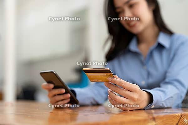 Young woman has a credit card and uses her smartphone for online shopping. Online Payment Shopping Concept [IBR125382658]
