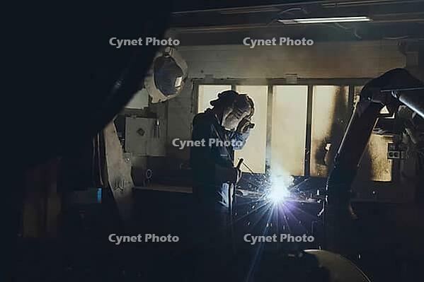 A welder in a workshop welds a part [IBR125405066]