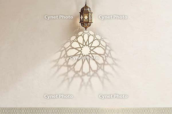 Traditional ornate hanging lantern casting a beautiful Islamic geometric shadow on a textured beige wall, AI generated [IBR125407387]