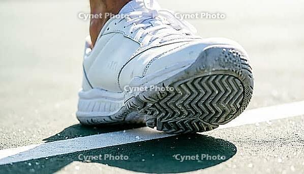 Close-up of a white tennis shoe's herringbone tread sole pressed against a hard court surface along a painted white baseline, bright natural daylight, sports footwork concept, AI generated [IBR125407446]