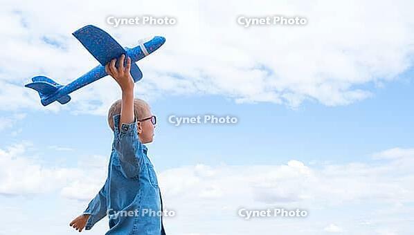 Rear view of boy with airplane dreaming of traveling in nature against blue sky in summer [IBR125411071]