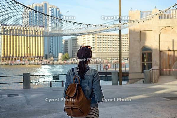 A young traveler is walking and enjoying the old narrow streets of Dubai Deira and Creek. Travel and sightseeing concept [IBR125411090]