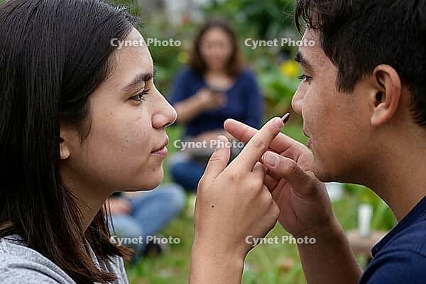 Interpersonal intimacy and tactile connection between young adults in a park, nonverbal communication during authentic emotional dialogue, direct eye contact and playful physical gesture between two friends symbolise immediate sensory presence, the finger [IBR125414129]