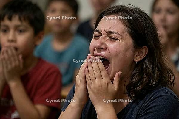 Collective trauma and raw human grief during a devastating crisis, intense emotional distress manifests through an agonizing scream of a weeping woman, hands clasped near her open mouth as tears stream down tightly shut eyes, overwhelming psychological sh [IBR125414131]