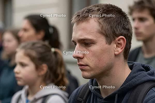 Pensive young man standing in a focused crowd outdoors, thoughtful gaze reflecting social pressure and generational anxiety, deep contemplation during public gathering, emotional resonance of youth confronting economic precarity, psychological stress and  [IBR125414144]