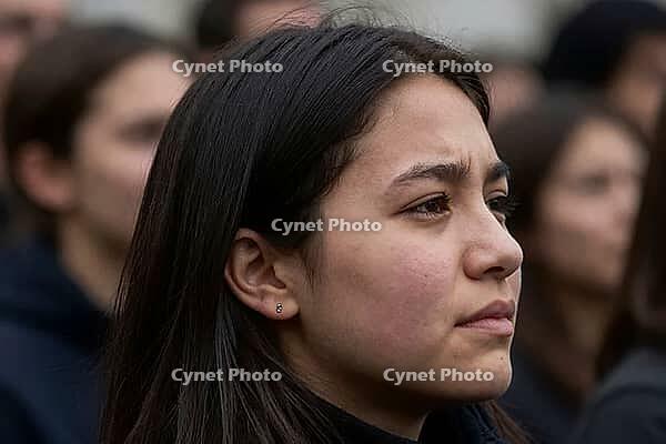 Young woman demonstrating attentive civic engagement among crowd of people, thoughtful facial expression during public gathering for civil rights, deep concentration reflecting political participation and social consciousness, subtle emotional nuance of e [IBR125414156]