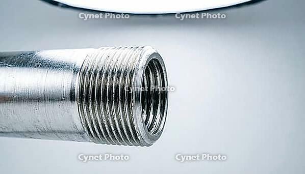 Close-up of a freshly machined steel pipe threaded end with crisp trapezoidal thread grooves on pale grey studio background, precision engineering, industrial macro photography, AI generated [IBR125414158]