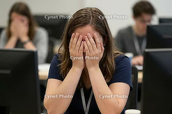 Workplace stress, corporate burnout, cognitive overload, digital exhaustion, employee despair, mental health crisis at computer workstation, young female professional hiding face in hands between desktop screens, profound psychological strain and anxiety  [IBR125414163]