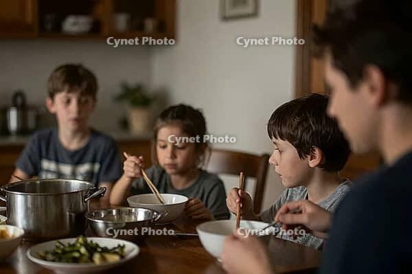 Family mealtime with siblings eating warm lunch together around rustic dining table using wooden chopsticks, nourishing home cooked food in bowls, quiet domestic gathering during daytime, child nutrition, commensality as social cohesion in everyday home l [IBR125414178]