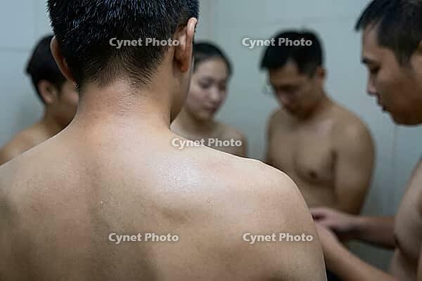 Somatic vulnerability, collective exposure and human intimacy in an enclosed communal environment, young adults standing together with bare skin, close physical proximity creating intense social tension and emotional bonding, the tactile warmth of bare sh [IBR125414191]
