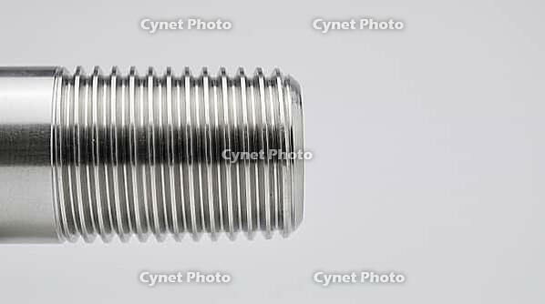 Close-up of a freshly machined steel pipe threaded end with crisp trapezoidal thread grooves on pale grey studio background, precision engineering, industrial macro photography, AI generated [IBR125414205]