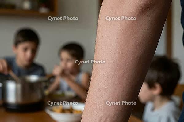 Domestic care work and parental exhaustion in modern family life, close up skin texture of adult arm framing children eating at dining table, somatic manifestation of invisible reproductive labor in the private sphere, young boys having lunch together fro [IBR125414213]