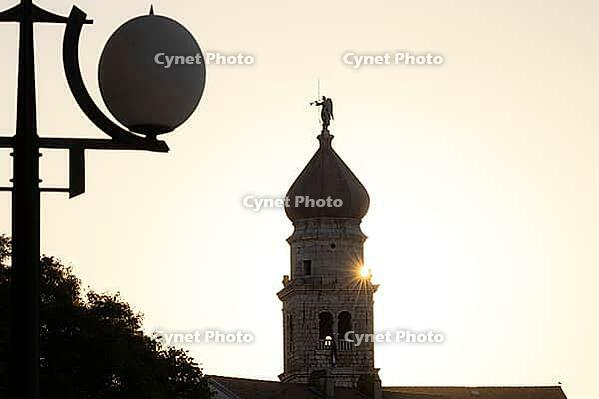 Sunrise behind the bell tower of the Assumption Cathedral with baroque onion dome and trumpet blowing angel, old town of Krk, island of Krk, Croatia [IBR125415365]