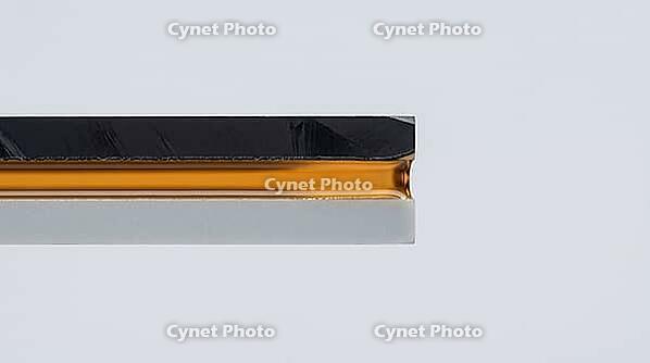 Extreme macro cross-section of a narrow gap between silicon chip and ceramic substrate completely filled with translucent amber cured epoxy underfill, semiconductor packaging photography, AI generated [IBR125421199]