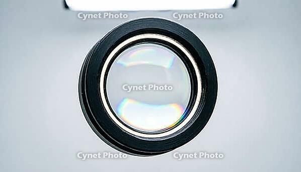 Close-up of a circular optical lens element with iridescent anti-reflective coating mounted in a matte black housing, spectrometer optics photography, clinical studio lighting, AI generated [IBR125421214]