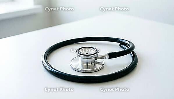 Coiled stainless steel stethoscope with black rubber tubing on a plain white clinical countertop, cardiac monitoring equipment, soft natural daylight, studio photography, AI generated [IBR125421219]