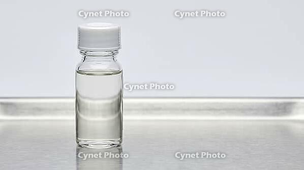 Clear glass sensor calibration reference vial with colorless liquid on a stainless steel tray, clinical laboratory studio lighting, analytical instrumentation photography, AI generated [IBR125421256]