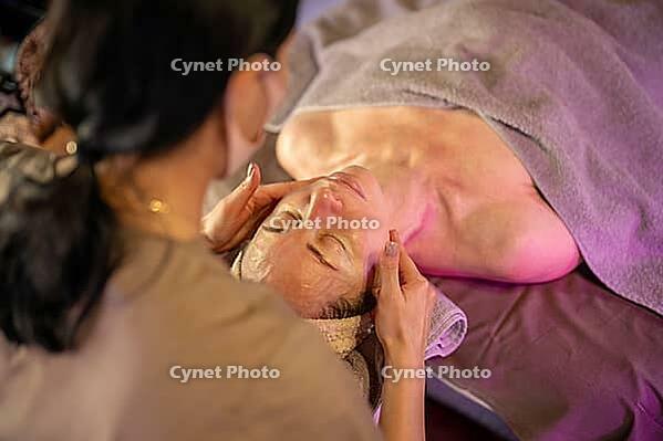 Professional dermatologist making relaxing beauty facial massage for woman lying on table under towel, female patient enjoying lifting drainage massage session, self love and feminine beauty rituals [IBR125421629]