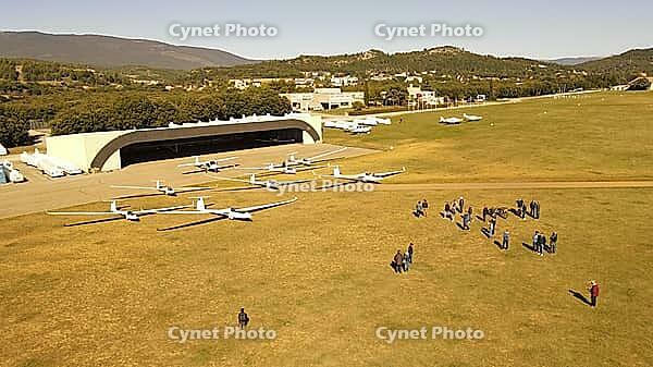 Gliders and people near hangars on an airfield, with hills in the distance, - dp - Aérodrome de Château-Arnoux - Saint-Auban, France [IBR125421644]