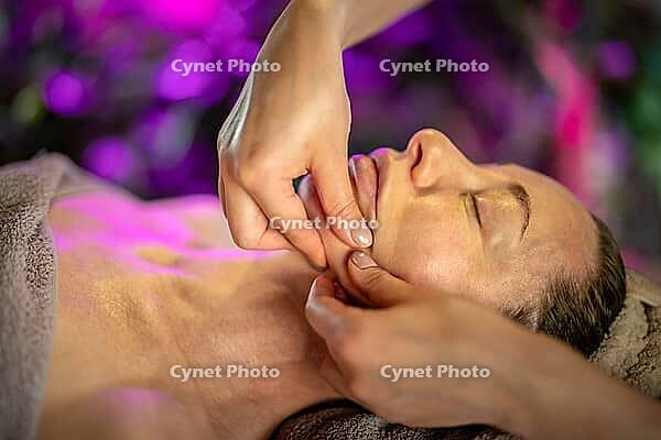 Relaxed woman receiving facial massage from professional cosmetologist masseuse in luxury spa clinic, therapist using fingers massaging female client face for better lymphatic drainage and lifting [IBR125421685]