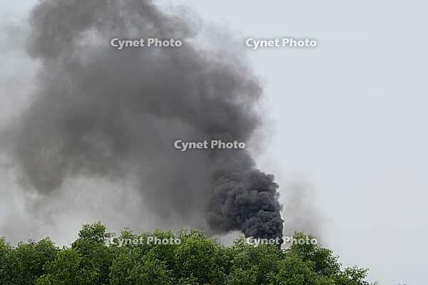 Thick black smoke spewing from an industrial chimney above green trees Sreepur, Gazipur, Bangladesh [IBR125423491]