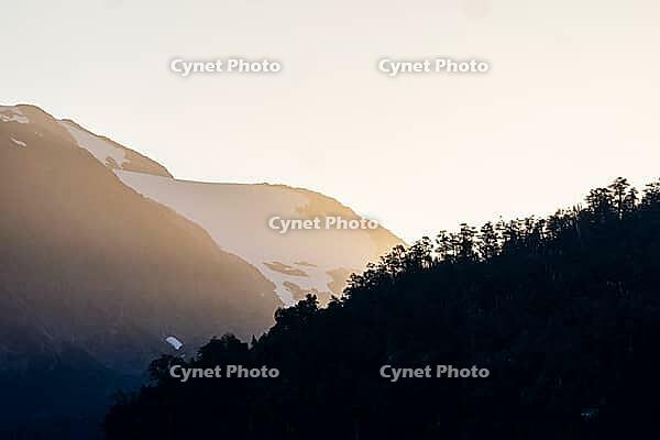 Mountains with forest and glaciated mountain peaks at sunrise, Carretera Austral, near Villa Santa Lucia, Los Lagos, Chile [IBR125423514]