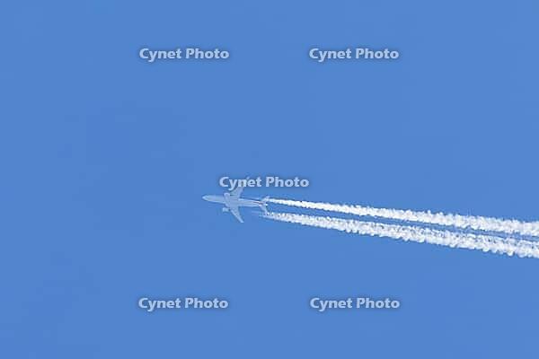 Jet commercial passenger aircraft flying in a blue sky with contrails or vapour trails behind in the atmosphere, England, United Kingdom [IBR125423517]