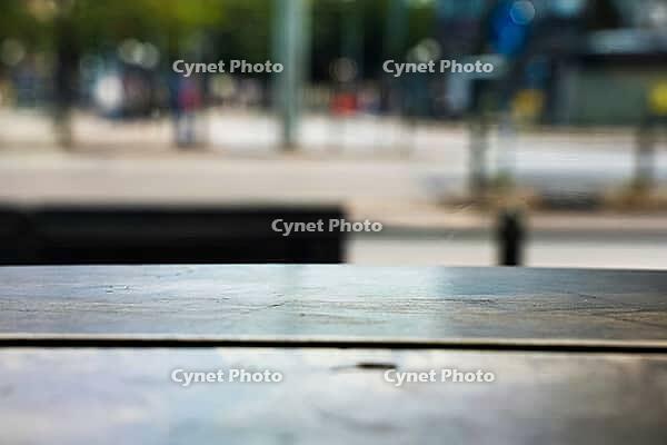 Empty wooden table surface in foreground with a blurry urban street scene backdrop [IBR125424538]