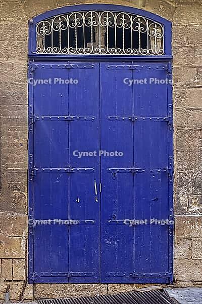 An old wooden blue door in a Mediterranean setting in a historic town in Italien [IBR125436226]