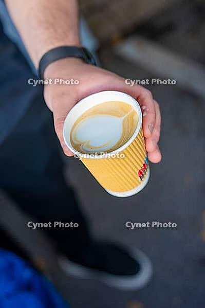 A hand presents a mug of latte art on a street, Sindelfingen, Germany [IBR125436244]