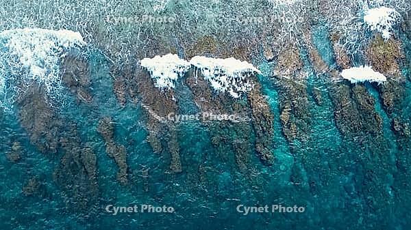 Ocean waves breaking over a beautiful shallow coral reef creating natural patterns in the turquoise water [IBR125436281]
