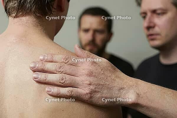 Emotional support and male vulnerability through a gentle hand on a bare shoulder, conveying empathy, brotherhood, grief processing, mental health, interpersonal tactile communication establishes psychological comfort between distressed individuals, the e [IBR125446424]
