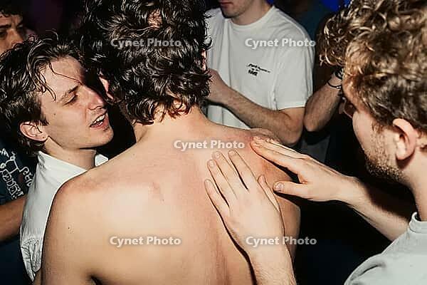 Tactile connection, nocturnal hedonism, youth subculture and authentic emotional intimacy unite during crowded club party celebrations, bare skin contact beneath harsh flash illumination embodies vulnerability, kinetic energy within crowded underground ga [IBR125446428]