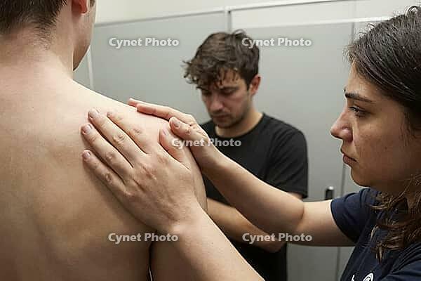 Manual physical therapy examination and shoulder palpation in modern clinical rehabilitation, diagnostic assessment of musculoskeletal tension, a professional therapist gently evaluates the deltoid and scapular region of a bare young male patient, tactile [IBR125446431]