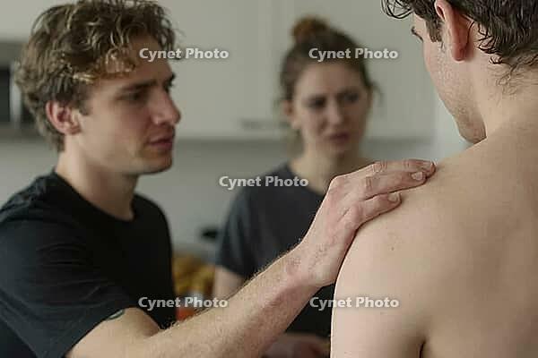 Interpersonal psychological crisis, empathy and solidarity among young adults, empathetic hand gesture on bare shoulder showing nonverbal reassurance, concerned facial expressions indicating relational tension and emotional vulnerability, blurred female w [IBR125446451]