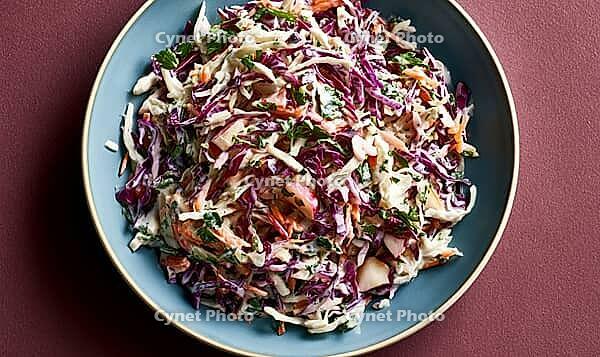 Fresh coleslaw salad with shredded purple cabbage, carrots, and herbs. Served on blue plate against deep red background, AI generated [IBR125446453]