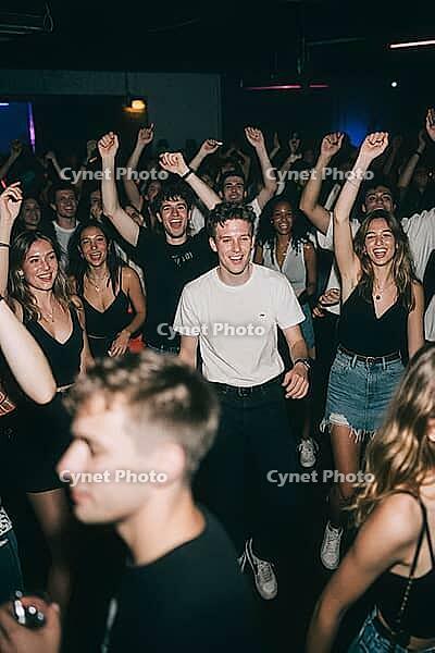 Euphoric young crowd dancing together in a vibrant nightclub atmosphere, celebrating youth culture, electronic dance music and social connection, raised arms and synchronized movements manifest the psychological release of dopamine and collective efferves [IBR125446460]