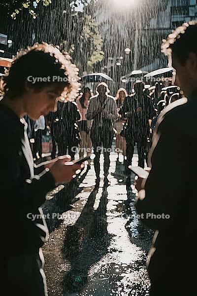 Digital connectivity meets urban isolation amidst heavy rainfall, pedestrians fixate on glowing smartphones while traversing wet city pavement, backlighting illuminates falling raindrops and casts long cast shadows along drenched asphalt, young men in the [IBR125446467]