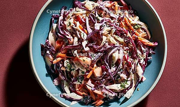 A bowl of vibrant coleslaw with red cabbage, carrots, and creamy dressing, served in a blue dish, AI generated [IBR125446472]