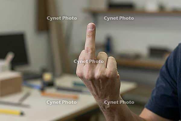 Workplace rebellion and intense frustration in a craft workshop, an anonymous person shows an explicit middle finger gesture toward authority, professional dissatisfaction and vocational stress collide with corporate pressure, hand anatomy reveals tension [IBR125446478]
