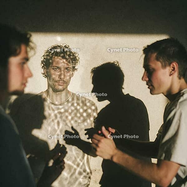 Interpersonal psychological resonance and perceptual duality unfold through illuminated human silhouettes, dynamic projection light revealing melancholic contemplation, young men interacting in deep ambient shadows, projected facial textures creating surr [IBR125446489]