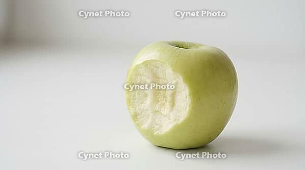Close-up of a clean bite mark with visible tooth impressions in a pale green apple, matte white surface, forensic odontology demonstration substrate photography, AI generated [IBR125446505]