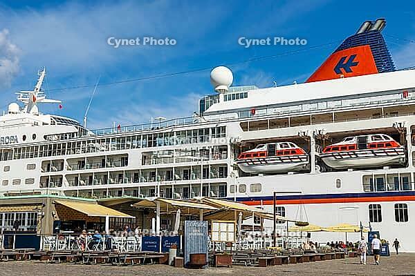 Seaside Toldboden restaurant with outdoor seating in front of cruise ship in port, summer, blue sky, Copenhagen, Denmark [IBR125448822]