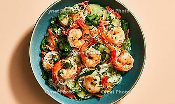 Shrimp and cucumber salad in blue bowl. Fresh herbs, rice noodles, and chili garnish. Vibrant colors, healthy meal concept, AI generated [IBR125448888]